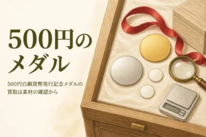 500円白銅貨幣発行記念メダルの買取のアイキャッチ。無地の銀色のメダルと硬貨、ルーペ、はかり