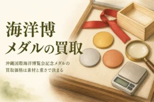 無地の金色・銀色・銅色のメダルとはかりのイメージ、「海洋博メダルの買取」の文字