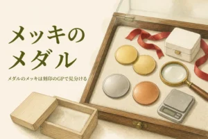 無地の金色のメダルとルーペのイメージ、「メッキのメダル」の文字