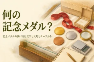 無地のメダルと小箱・ルーペ・メモ帳のイメージ、「何の記念メダル？」の文字