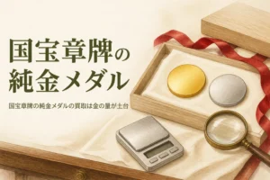 国宝章牌の純金メダルの買取のアイキャッチ。無地の金色と銀色のメダルと木箱、はかり